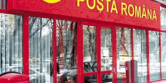 Front of a Poșta Română post office with a red facade, glass doors, and a red mailbox outside in the snow.